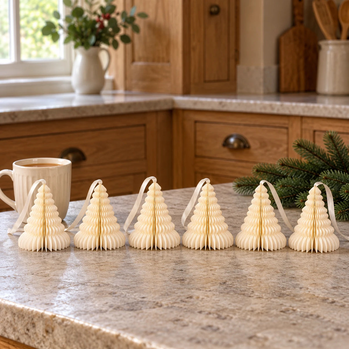 Six 11cm winter white paper tree ornaments on a kitchen counter beside tea.