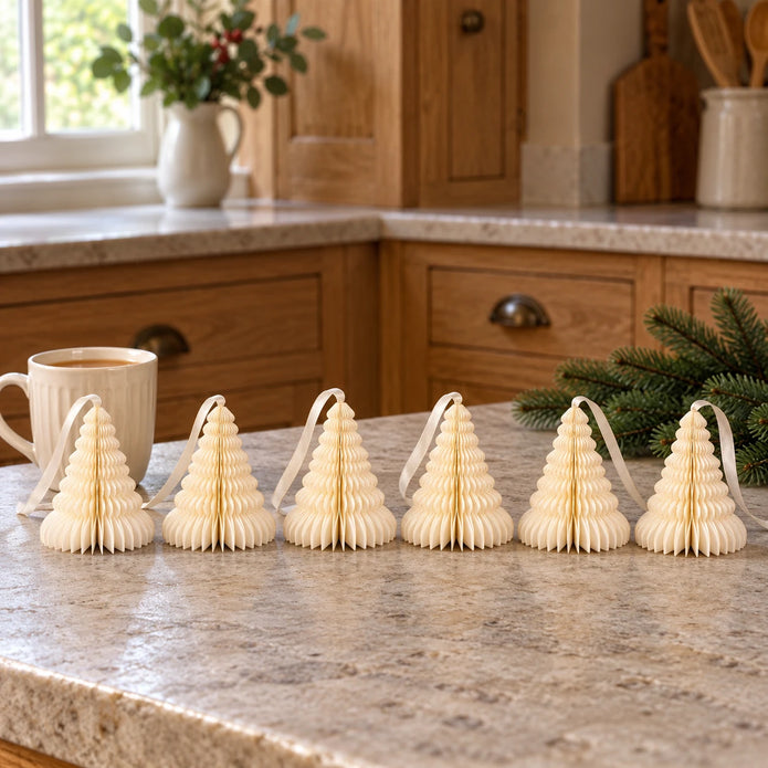 Six 11cm winter white paper tree ornaments on a kitchen counter beside tea.