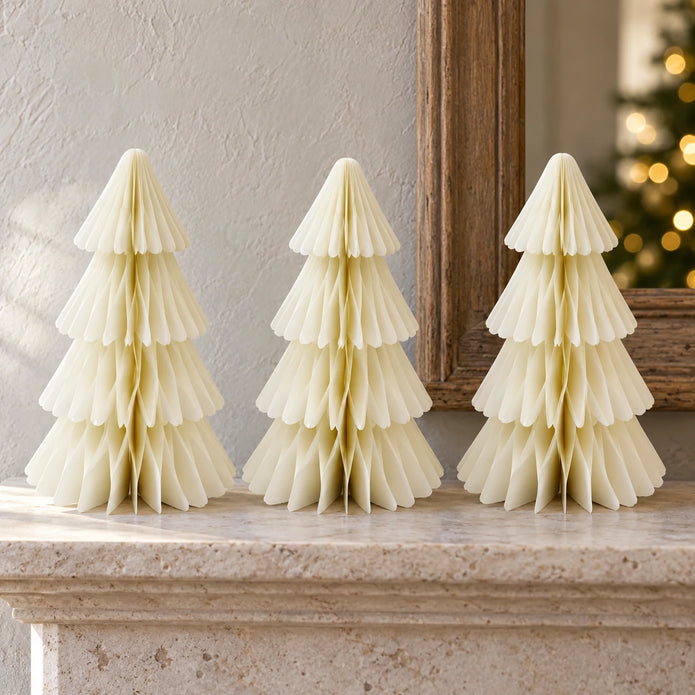 Three matching winter white paper Christmas trees displayed on a pale stone mantel.