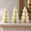 Three matching winter white paper Christmas trees displayed on a pale stone mantel.