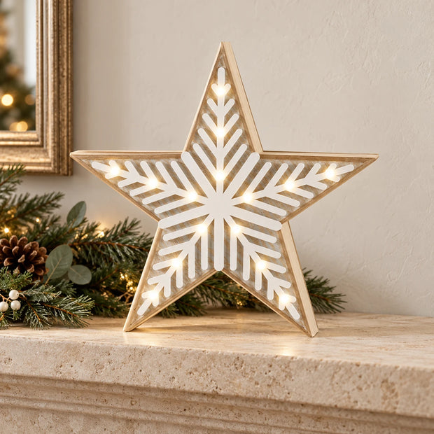 Medium wooden LED chevron star illuminated on a limestone mantel with Christmas greenery.