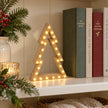 Small wooden LED nested tree on a cream bookshelf.