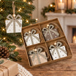 Cream wooden present decoration hanging on a Christmas tree.