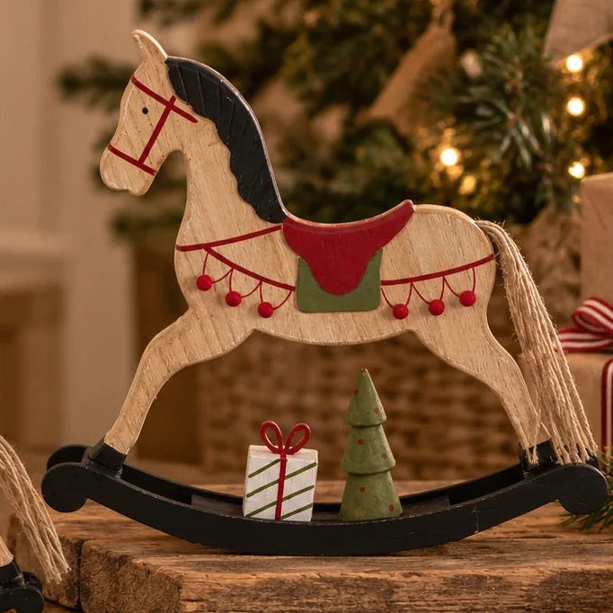 Two wooden rocking horse Christmas decorations styled beside a neutral Christmas tree with fairy lights