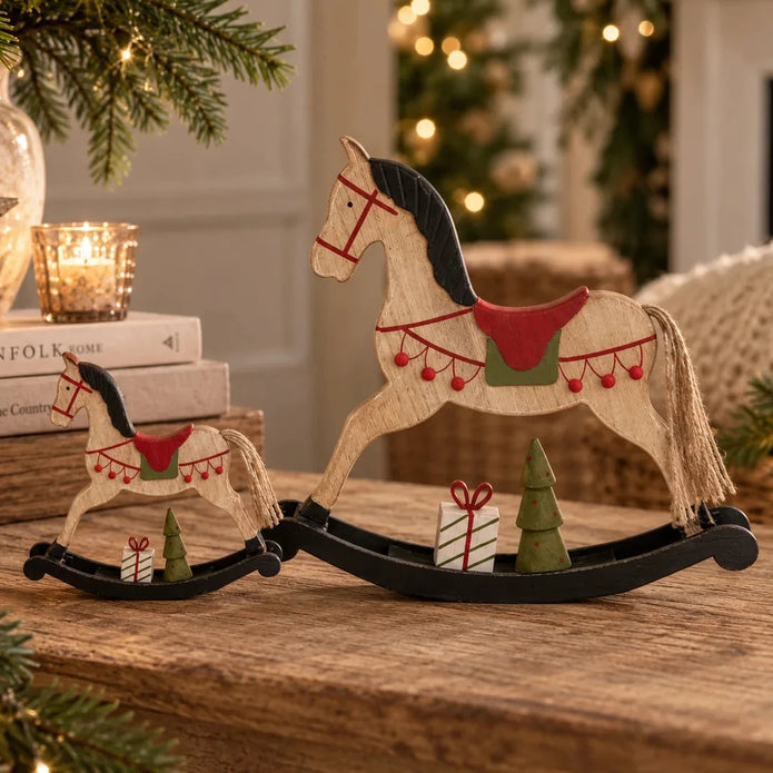Small and large wooden rocking horse ornaments on a country home mantel with natural greenery